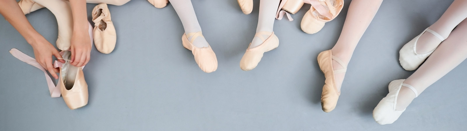 Les cours de danse de l'académie de Nivelles représentés par des chaussons de danse portés par de petites danseuses